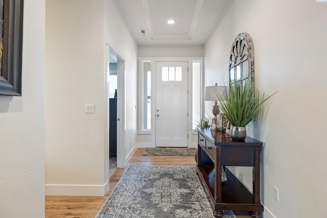 entryway featuring baseboards, wood finished floors, visible vents, and a healthy amount of sunlight