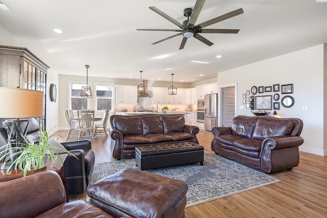 living area featuring light wood-type flooring, ceiling fan, baseboards, and recessed lighting