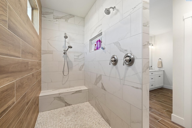 bathroom with a tile shower, vanity, and wood finished floors