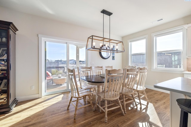 dining space featuring light wood finished floors, baseboards, visible vents, and an inviting chandelier