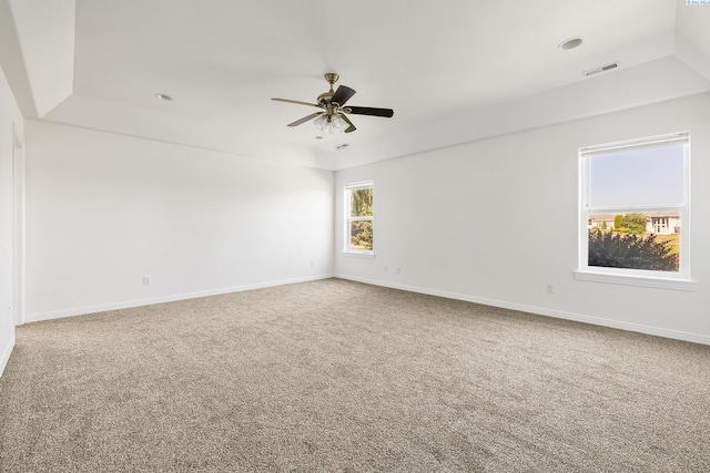 carpeted spare room featuring baseboards, visible vents, and a ceiling fan