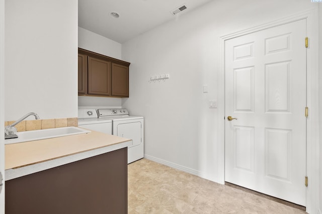 clothes washing area with a sink, visible vents, baseboards, independent washer and dryer, and cabinet space