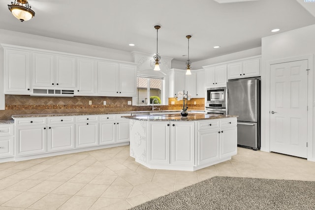 kitchen featuring a center island, pendant lighting, stainless steel appliances, white cabinetry, and dark stone counters