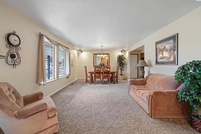 carpeted living area with a textured ceiling, a chandelier, and baseboards