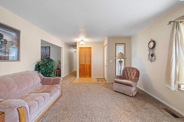 living room with baseboards, a textured ceiling, visible vents, and light colored carpet