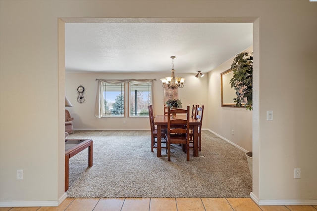 dining space featuring light colored carpet, a notable chandelier, a textured ceiling, and baseboards