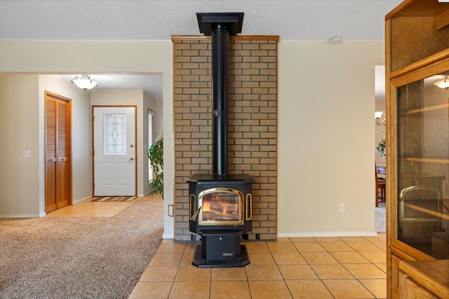 living room featuring baseboards, light tile patterned flooring, a wood stove, and light colored carpet