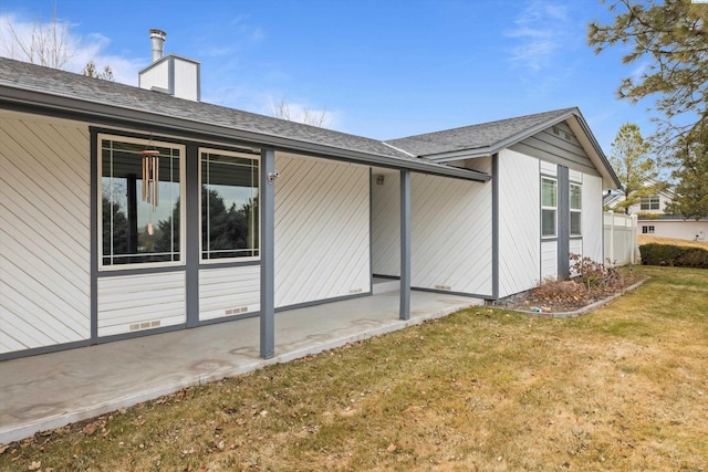 back of property featuring roof with shingles, a yard, a chimney, crawl space, and a patio area