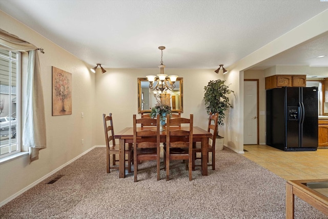 dining area with light carpet, a wealth of natural light, and a notable chandelier