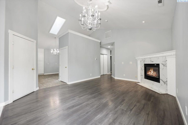 823 S 5th Ave, Pasco, WA 99301 - unfurnished living room with a chandelier, high vaulted ceiling, a premium fireplace, wood finished floors, and a skylight