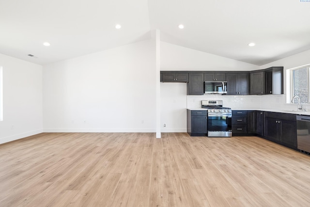2925 S Osborne St, Kennewick, WA 99338 - kitchen featuring appliances with stainless steel finishes, lofted ceiling, light countertops, decorative backsplash, and light wood-style floors