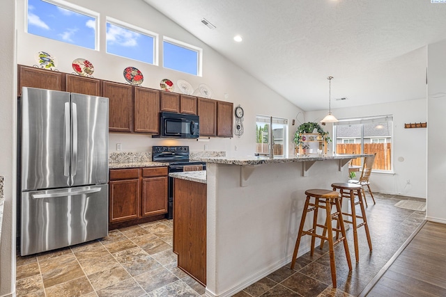 6110 Westport Ln, Pasco, WA 99301 - kitchen featuring black appliances, high vaulted ceiling, pendant lighting, a breakfast bar area, and a kitchen island with sink