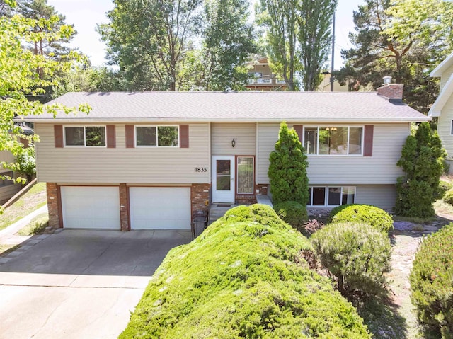 1835 NW Deane St, Pullman, WA 99163 - bi-level home featuring a garage, driveway, brick siding, a chimney, and roof with shingles