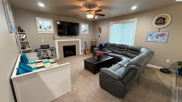 carpeted living room with ceiling fan, a healthy amount of sunlight, and a tiled fireplace