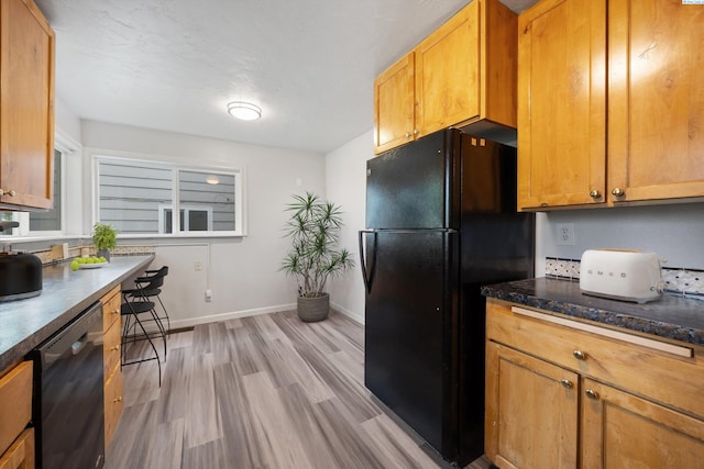 312 Mccabe St, Walla Walla, WA 99362 - kitchen featuring black appliances, light wood-style flooring, baseboards, brown cabinets, and dark stone counters