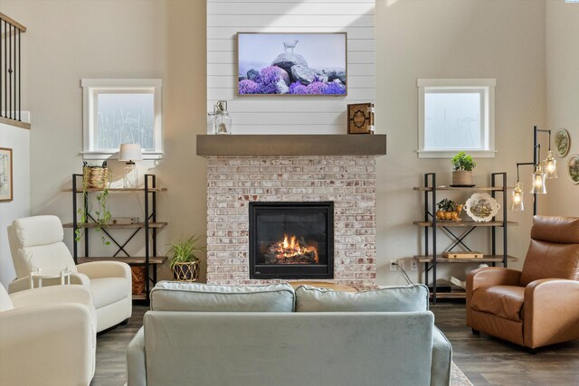 living area with dark wood-type flooring and a brick fireplace