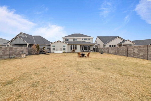 back of house with a lawn and a fenced backyard