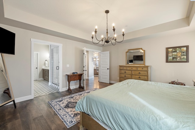 bedroom featuring baseboards, a raised ceiling, dark wood-style flooring, and ensuite bathroom