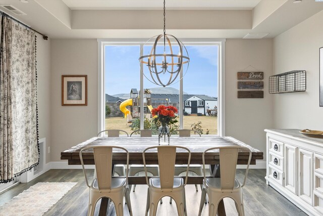 dining area with plenty of natural light, wood finished floors, visible vents, and a notable chandelier