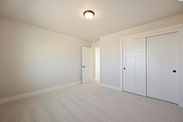 unfurnished bedroom with light colored carpet and a closet