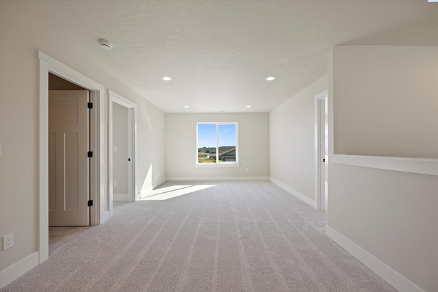 spare room featuring light carpet and a textured ceiling