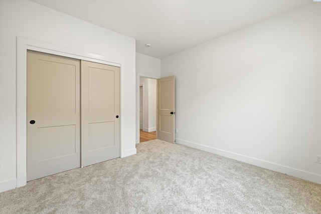 unfurnished bedroom featuring light carpet and a closet