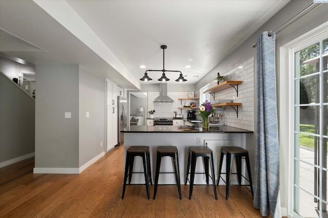2330 Hummingbird Ln, West Richland, WA 99353 - kitchen with open shelves, backsplash, wall chimney exhaust hood, dark countertops, and a peninsula