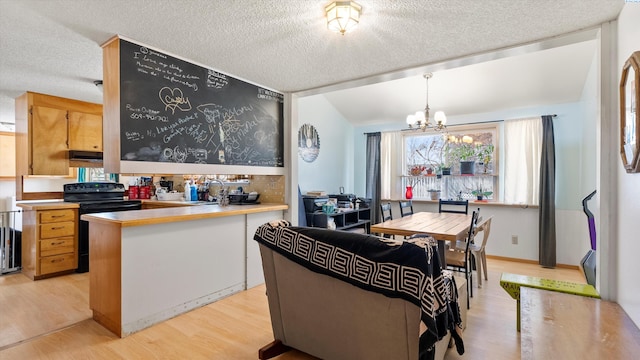 2113 Rainier Ave, Richland, WA 99354 - kitchen with a notable chandelier, a sink, black / electric stove, a peninsula, and light wood finished floors