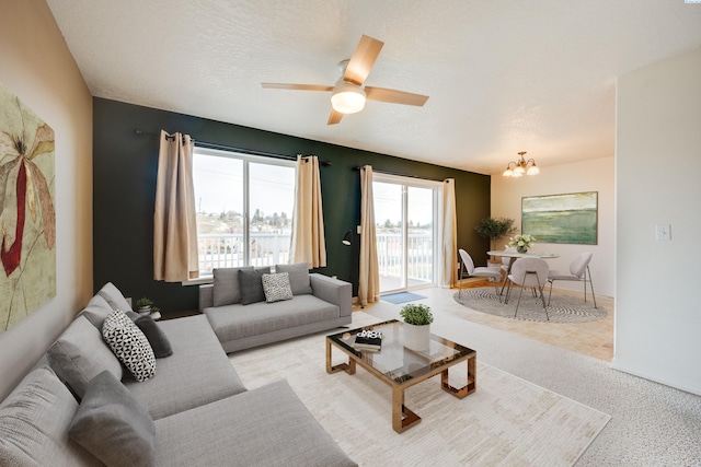 living room with ceiling fan with notable chandelier and a textured ceiling