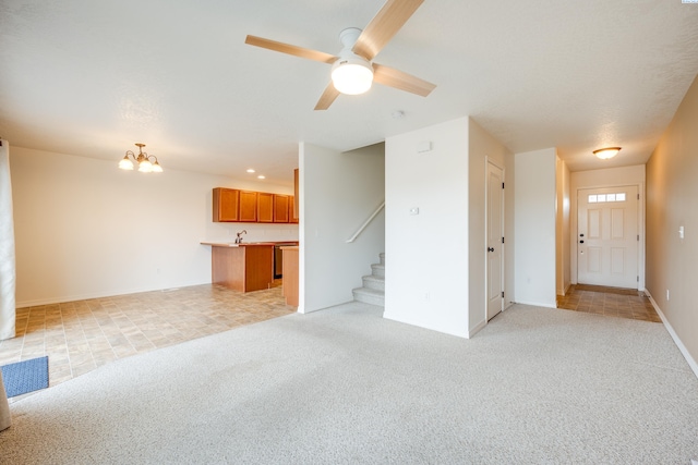 unfurnished living room featuring light carpet and ceiling fan with notable chandelier