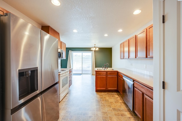 kitchen featuring appliances with stainless steel finishes, sink, a textured ceiling, and kitchen peninsula