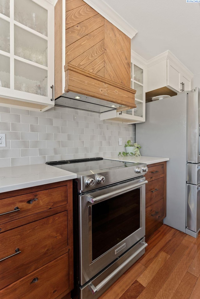 3202 S Palouse River Rd, Colfax, WA 99111 - kitchen with appliances with stainless steel finishes, premium range hood, glass insert cabinets, wood finished floors, and brown cabinets