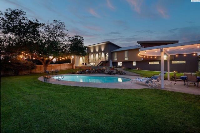 pool at dusk featuring a patio and a yard