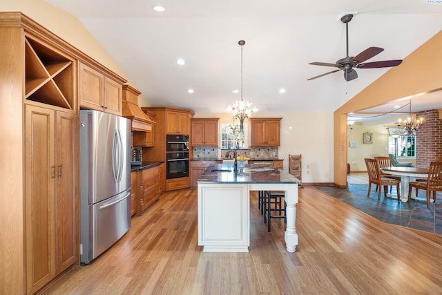 1515 Hains Ave, Richland, WA 99354 - kitchen featuring lofted ceiling, a breakfast bar, a sink, freestanding refrigerator, and brown cabinetry