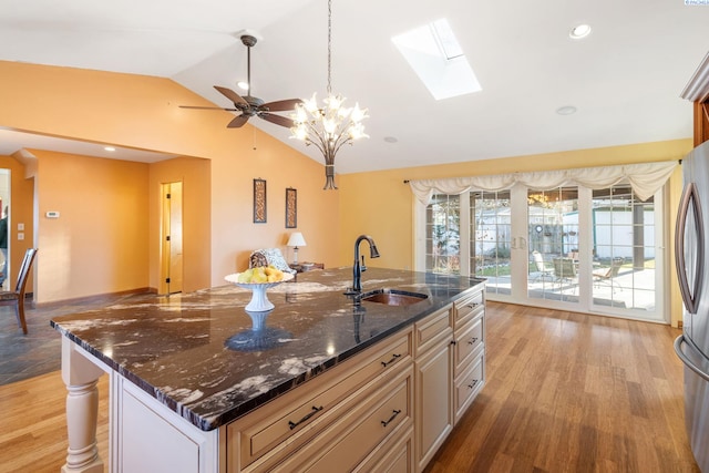 1515 Hains Ave, Richland, WA 99354 - kitchen with vaulted ceiling with skylight, dark stone counters, an island with sink, light wood-style floors, and a sink