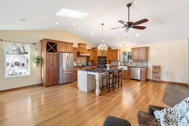 1515 Hains Ave, Richland, WA 99354 - kitchen featuring stainless steel appliances, decorative backsplash, lofted ceiling with skylight, premium range hood, and a kitchen breakfast bar