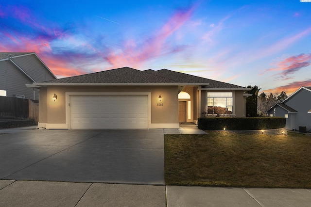 ranch-style home with stucco siding, concrete driveway, a front yard, fence, and a garage