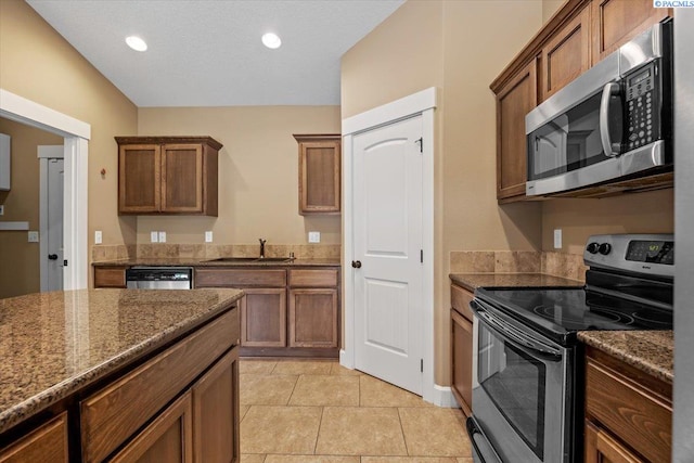 5709 W 23rd Ave, Kennewick, WA 99338 - kitchen with stainless steel appliances, dark stone countertops, light tile patterned floors, brown cabinets, and recessed lighting