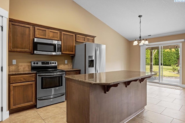 5709 W 23rd Ave, Kennewick, WA 99338 - kitchen featuring stainless steel appliances, vaulted ceiling, a center island, light tile patterned flooring, and a breakfast bar area