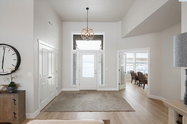 foyer with a high ceiling, light wood-type flooring, and an inviting chandelier