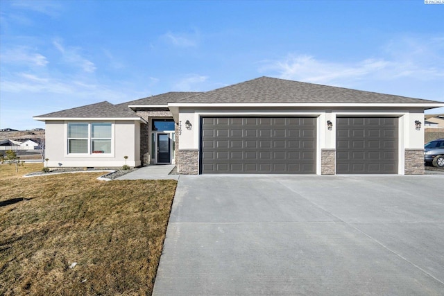 prairie-style home with driveway, stone siding, an attached garage, a front yard, and stucco siding