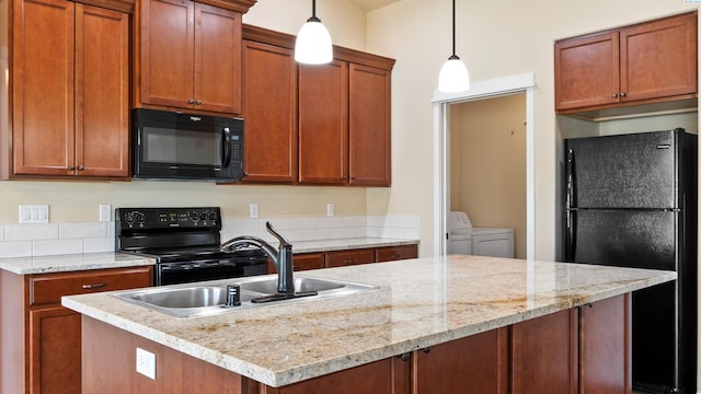 3245 S Palouse St, Kennewick, WA 99337 - kitchen featuring black appliances, washer and dryer, hanging light fixtures, a sink, and an island with sink