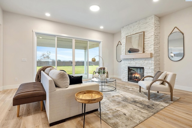 living room featuring a stone fireplace and light wood-type flooring