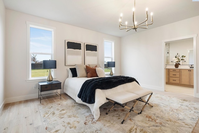 bedroom featuring connected bathroom, a notable chandelier, and light hardwood / wood-style floors