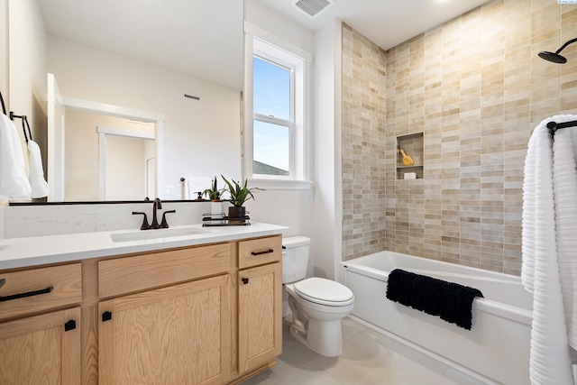 full bathroom featuring tile patterned flooring, tiled shower / bath, vanity, and toilet