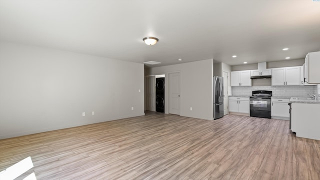 414 Whitefish Ln, Pasco, WA 99301 - kitchen with stacked washer / dryer, black range with electric stovetop, freestanding refrigerator, open floor plan, and tasteful backsplash