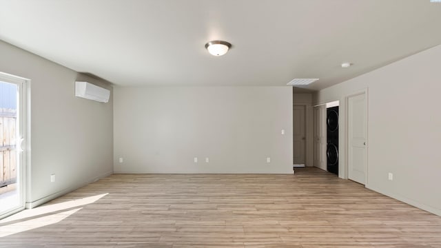 414 Whitefish Ln, Pasco, WA 99301 - unfurnished room featuring stacked washing machine and dryer, light wood-style floors, an AC wall unit, and baseboards