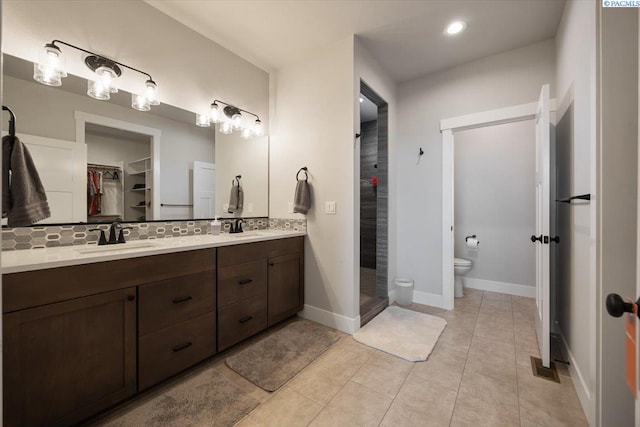 5770 W 40th Ave, Kennewick, WA 99338 - full bathroom with double vanity, backsplash, a stall shower, a spacious closet, and tile patterned floors