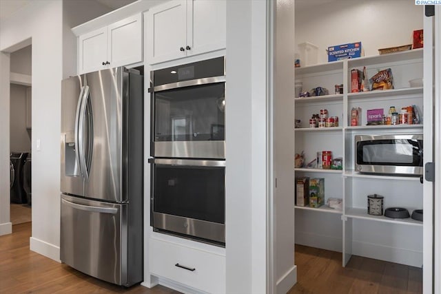 5770 W 40th Ave, Kennewick, WA 99338 - kitchen featuring stainless steel appliances, independent washer and dryer, wood finished floors, and white cabinetry