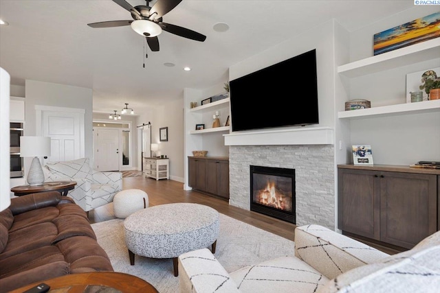 5770 W 40th Ave, Kennewick, WA 99338 - living area with a ceiling fan, wood finished floors, a stone fireplace, built in features, and recessed lighting